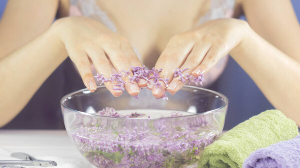 Hands of a woman in a bath with flowers. Manicure, nail SPA. Sensuality, skincare, feminine, salon, wash, wealth, therapy, cosmetics, treatment, relax, dayspa, aromatherapy