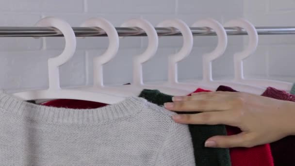 Swetry Wieszakach Zbliżenie Żeńskich Rąk Wyrwało Wieszak Ubraniami Ręce Kobiety — Wideo stockowe