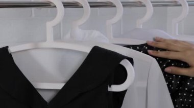 Beyaz bir bluz seç. Kadın bir kıyafet seçer. Kadın kıyafetleri askıda asılı. Klasik tarz, ofis, kadınsı. Kıyafet almak, alışveriş yapmak. Temel gardırop, minimalizm. Askıdan bir bluz al.