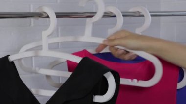Kadın gergin ve bluzunu askıya asamıyor. Elbiseler askıda asılı. Acele etmek, geç kalmak. Dolabı temizle. Minimalizm. Basit bir gardırop. Klasik tarz, kadınsı, ofis.