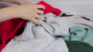 Bir yığın giysinin içinde doğru kazağı ara. Berbat bir durum. Dolabı temizliyorum. Elbiseleri ayır. Acele etmek, geç kalmak. Çok renkli kazaklar, kadın giysileri..