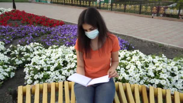 Una Chica Con Máscara Médica Lee Libro Banco Distancia Social — Vídeo de stock