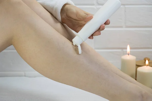 Apply depilatory cream to your legs. Beauty, treatment. Skin care at home. Hairy legs and body positive, anti-shave, feminism. Ingrown hair and strawberry legs. Preparation for hair removal.