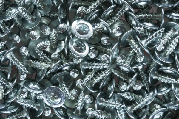Metallic texture background. Screws and cogs. Tools for fixing and repairing. Stainless steel bolts. Galvanized metal fasteners. Pile of metal screws close up. Background of the bolts. Tapping screw.