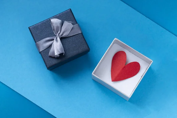 background for Valentines day holiday, gift for Valentines day, heart and gift box on blue background