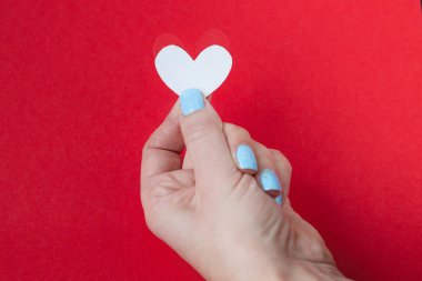 kırmızı bir arka plan üzerinde beyaz bir kalp tutan el. Sevgililer günü için arka plan