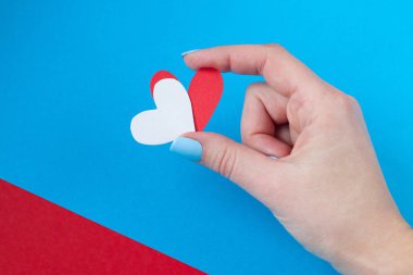 kırmızı ve mavi bir arka plan üzerinde kırmızı ve beyaz kalp tutan el. Sevgililer günü için arka plan