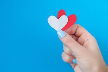 mavi bir arka plan üzerinde kırmızı ve beyaz kalp tutan el. Sevgililer günü için arka plan