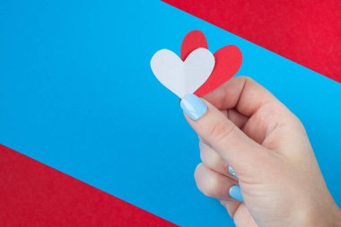 kırmızı ve mavi bir arka plan üzerinde kırmızı ve beyaz kalp tutan el. Sevgililer günü için arka plan