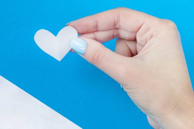 beyaz ve mavi bir arka plan üzerinde beyaz bir kalp tutan el. Sevgililer günü için arka plan