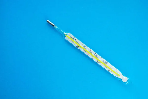medical mercury thermometer on a blue background, glass thermometer. place for text