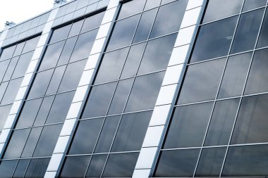 Kare mavi camlı modern cam bir binanın yakın çekimi.