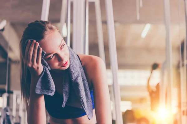 stock image Tired woman from workout wiping sweat with towel in sports gym 