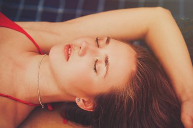 Havuz kenarında yalan bikinili güzel genç kadın Sunbathing