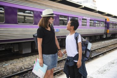Asya sırt çantası gezgin kadın oğluyla bir tren istasyonunda platformunda