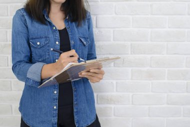 Bir defter ve bir kalem bir beyaz duvara yakın duran notlar almaya hazır tutan eller kadın