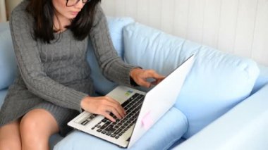 Asyalı kadın kanepede oturan ve dizüstü evde kullanma