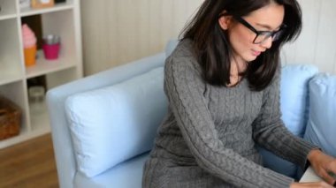 Kanepede oturan ve evde laptop yazarak Asyalı kadın