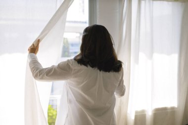 Pencere perdeleri açmayı mutlu Asyalı kadın