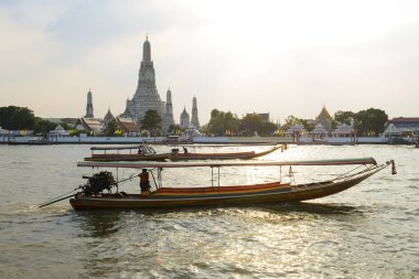 Tekneler ve Wat Arun Tapınağı arka planda günbatımı ile Chao Phraya Nehri'nin görünümü