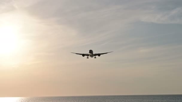 Caméra 4K suivre la silhouette d'un avion atterrissant au coucher ou au lever du soleil 