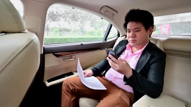 Азиатский Бизнесмен Разговаривает Мобильному Телефону Просматривает Документы Сидя Машине — стоковое видео