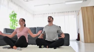 4K Genç çift mindere oturmuş yoga yapıyor. Evde nilüfer pozu veriyor ve nefes egzersizleri yapıyor.
