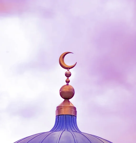 Golden Islamic symbol of crescent decorating top of mosque dome in pink color