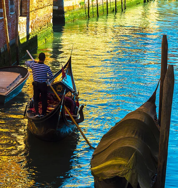 Гондольер гребёт на гондоле в венецианском канале летом — стоковое фото