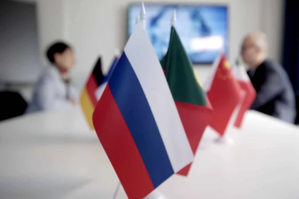 Blur effect. Meeting of management, meeting of directors. International commission, table with flags of EU, Russia and other countries.