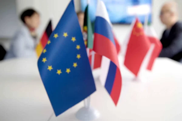 Blur effect. Meeting of management, meeting of directors. International commission, table with flags of EU, Russia and other countries.