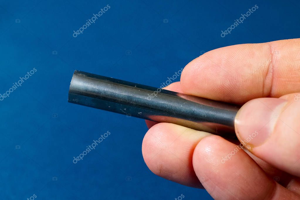 Varilla de tungsteno en la mano. Una pieza de tungsteno para experimentos. 2022