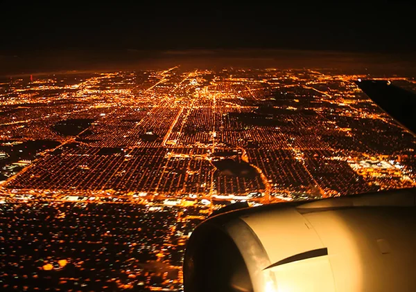 Flying over the night city by plane. The view from the window of a passenger plane during the flight, the wing of the turbine engine of the aircraft.