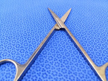 Mavi arka planda tıbbi cerrahi makas. Vida eklemlerine odaklanmış.