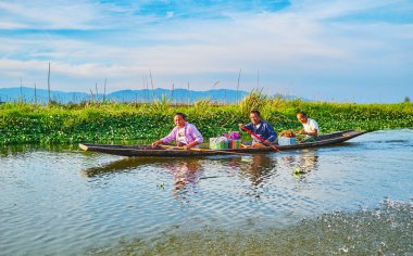 Inle Gölü, Myanmar - 18 Şubat 2018: Arka planda, 18 Şubat'ta Inle Gölü üzerinde kayan çiftlik manzaralı küçük kayık içinde kanal boyunca yaşlı köylüler kayan nokta.
