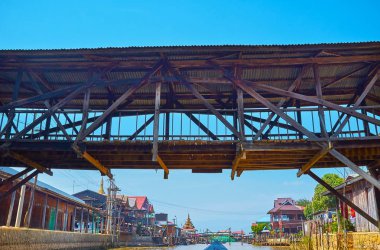 Inle Gölü dar kanal kıyısında, Ywama, Myanmar yoğun konut ile yukarıda eski ahşap köprü altında yüzen.