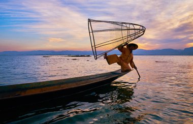 Intha, Myanmar - 18 Şubat 2018: Inle Gölü geleneksel balıkçı pozlar 18 Şubat Intha içinde arka planda, günbatımı gökyüzü ile Kano kenarına koni net ile hüner gösteren,.