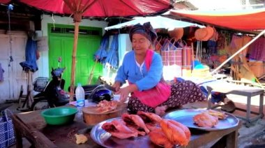 Taunggyi, Myanmar - 20 Şubat 2018: Gülümseyen yaşlı satıcı eski pazarının açık ahır masada oturur ve 20 Şubat Taunggyi içinde tavuk kadar keser.