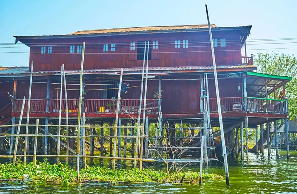 Traditional wooden stilt house with poles for mooring canoes, Inpawkhon village, Inle Lake, Myanmar.