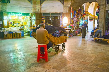 : Kerman, Iran - 15 Ekim 2017: Oturaklı hall, Ganjali Khan Grand ın Bazaarı kumaşların arabasını orta, 15 Ekim'de Kerman ile satıcı ile.