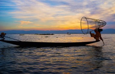 Inle Gölü günbatımı gezisinde yerel balıkçılar benzersiz tekniği tadını çıkarmak için en iyi seçimdir - bacak-kürek çekme onların yeteneklerini göstermek ve ilginç net, Myanmar ile balık yakalamak.