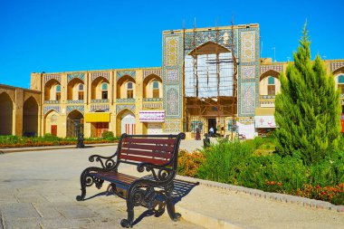 Kerman, Iran - 15 Ekim 2017: Kervansaray (Inn) doğal kiremitli portal 15 Ekim'de Kerman Ganjali Khan ile yeşil çiçek yatak ve banklar, kare yüzler.