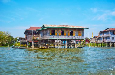 Kırsal sahne Inle Gölü - köylü stilts, Inpawkhon, Myanmar eski ahşap evin önünde kayık içinde yüzen.