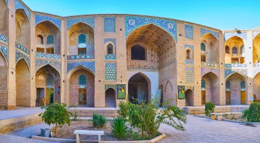 : Kerman, Iran - 15 Ekim 2017: Tarihsel Ganjali Han Kervansaray günümüzde pazar tezgahları, el sanatları atölye çalışmaları ve sanat galerileri, 15 Ekim'de Kerman içeren, avlunun ortasında küçük bahçe