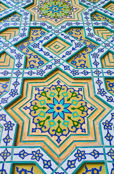 Close-up of the wall of Safe Azakhane Hussainiya with fine floral patterns of glazed tiles on stellar relief brick panel, Kerman, Iran.