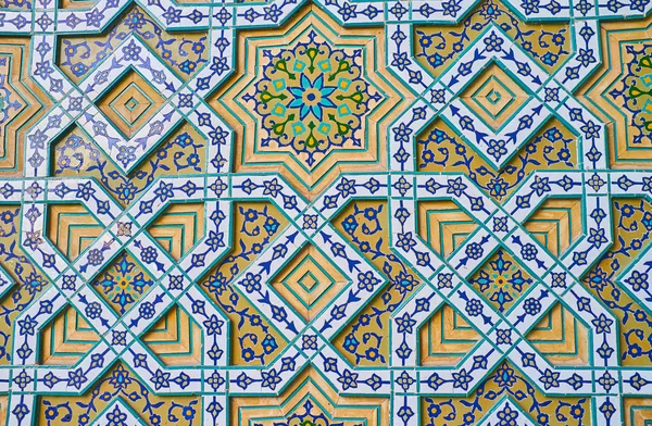 The gate wall of Safe Azakhane Hussainiya is covered with complex relief stellar pattern with floral tiled details, creating complex decoration in Persian style, Kerman, Iran.