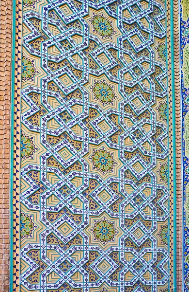 The wall of Safe Azakhane Mosque is covered with intricate Islamic patterns of glazed tiles and relief stellar details, Kerman, Iran.