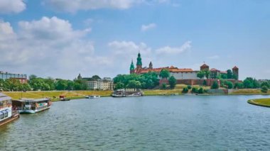 Yeşil bankanın Vistula Nehri'nin yüzen restoran ve Wawel Kalesi ile arka planda, Krakow, Polonya.