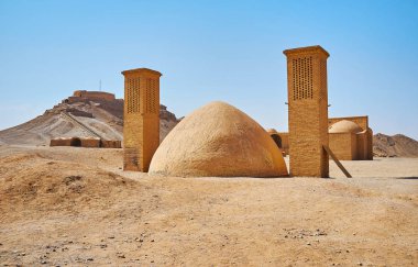 Yakhchal is the ancient evaporative cooler, the brick dome with two windtowers, located on hot desert grounds of Towers of Silence - the Zoroastrian burial site, Yazd, Iran.