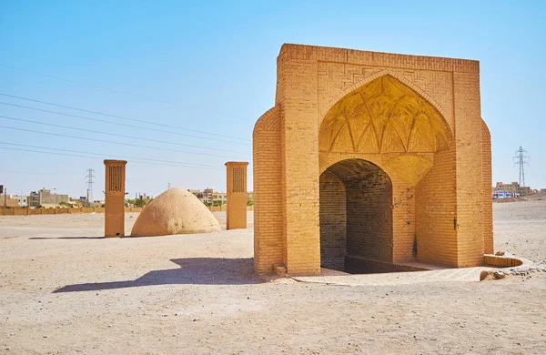 The brick portal leads to underground water cistern and the dome with windtowers on background is the ice chamber (yakhchal), located on desert grounds of Dakhma (Towers of Silence) Zoroastrian archaeological site, Yazd, Iran.